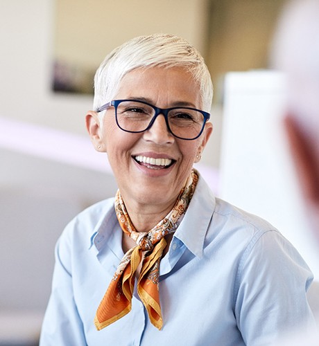 Senior woman with glasses smiling at man during work meeting