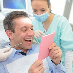 man looking at his new dental implants in Bettendorf