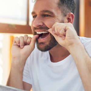 Man smiling while flossing his teeth