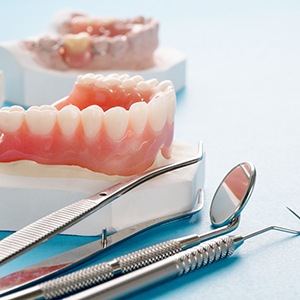 Several dentures on desk next to dental tools