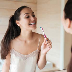 Woman brushing teeth to prevent dental emergency in Bettendorf