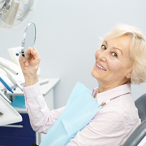 dental patient smiling at the camera with mirror in hand