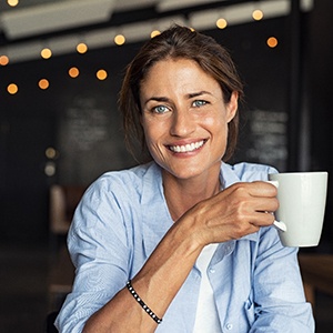 woman sitting in a coffee shop and holding a white mug