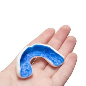 a blue mouthguard in a person’s hand