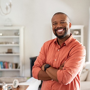 smiling man standing in his living room with his arms crossed