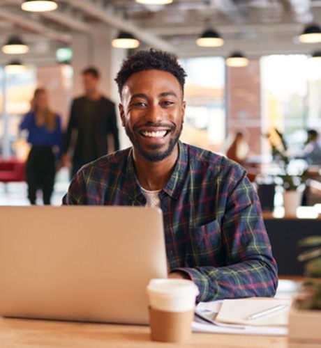 : Man smiling in office while working on laptop