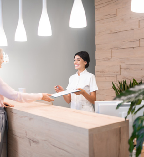 Patient smiling at dental receptionist in lobby