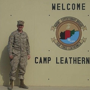 Dr. Pogue next to welcome to camp leatherneck sign