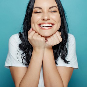 Woman smiling while touching her chin with her hands