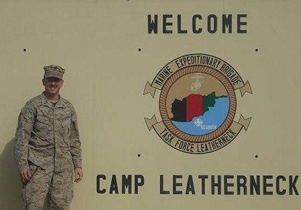 Soldier next to Welcome to Camp Leatherneck sign