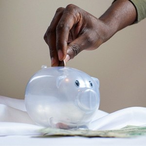 Hand putting coin in plastic piggy bank