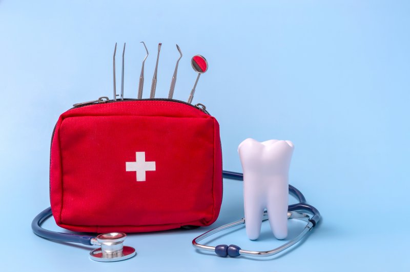 tooth next to stethoscope and emergency kit 