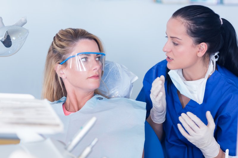 patient speaking with dentist about sensitive teeth with veneers
