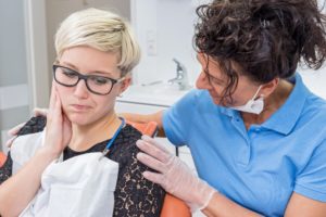Woman with dental pain being comforted by a dentist