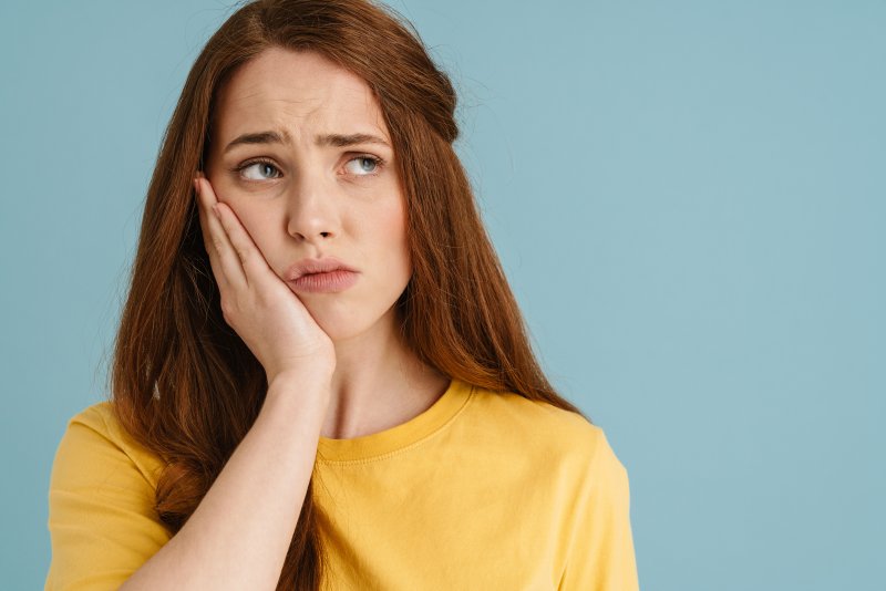 Patient holding their cheek after getting veneers